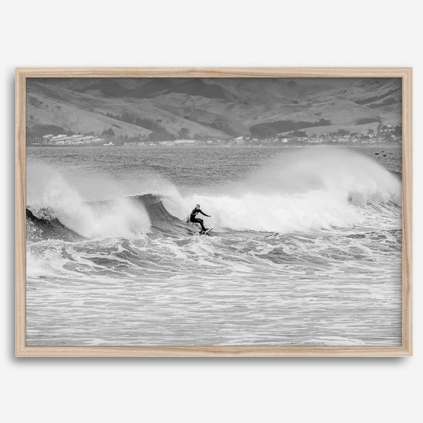 A black and white fine art surf print featuring a lone surfer riding the waves in Pismo Beach, California.
