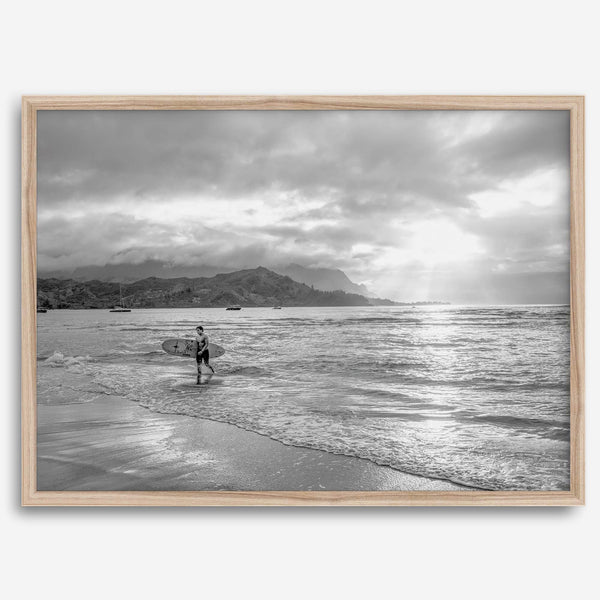 Surfer Wall Art featuring a lone surfer emerging from the ocean at Hanalei Bay in black-and-white photography.