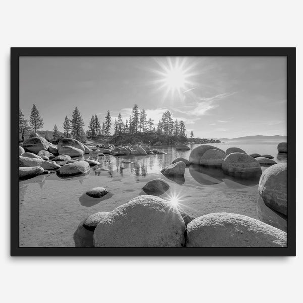 Capture the beauty of Lake Tahoe with this stunning black and white lake wall art. The image showcases majestic rocks rising from crystal-clear water. The reflection of the sun in the water adds a magical touch to the breathtaking scenery.