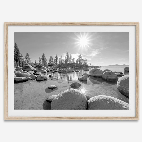 Capture the beauty of Lake Tahoe with this stunning black and white lake wall art. The image showcases majestic rocks rising from crystal-clear water. The reflection of the sun in the water adds a magical touch to the breathtaking scenery.