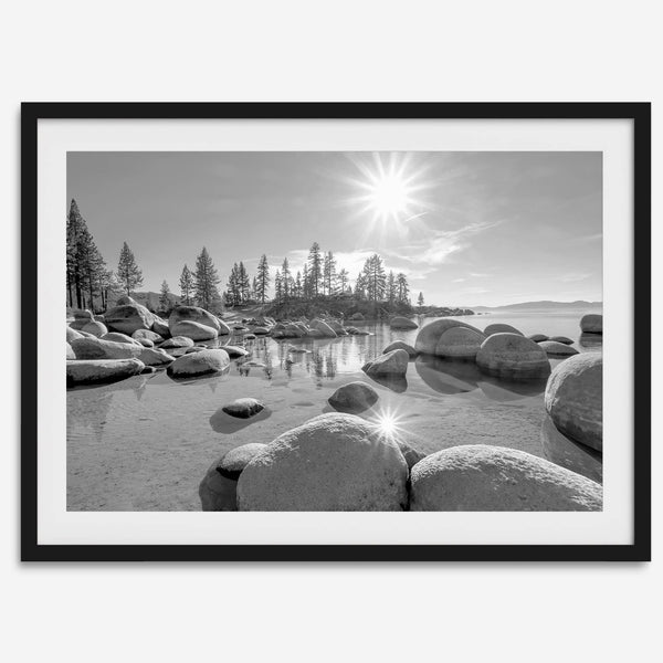 Capture the beauty of Lake Tahoe with this stunning black and white lake wall art. The image showcases majestic rocks rising from crystal-clear water. The reflection of the sun in the water adds a magical touch to the breathtaking scenery.