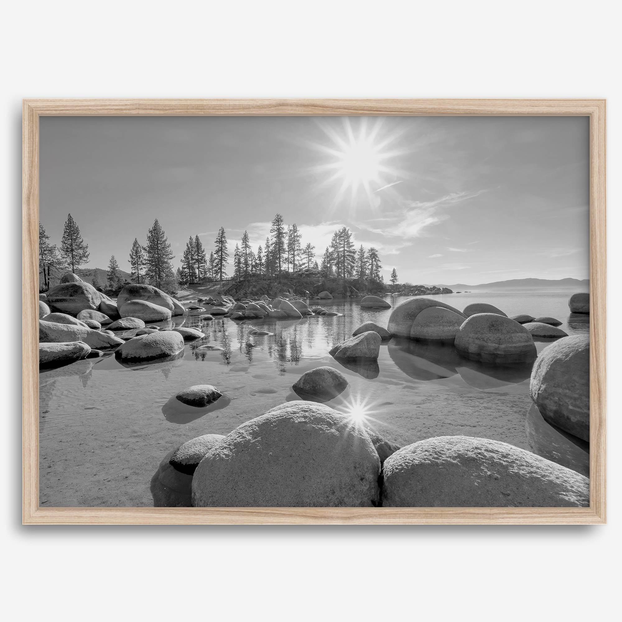 Capture the beauty of Lake Tahoe with this stunning black and white lake wall art. The image showcases majestic rocks rising from crystal-clear water. The reflection of the sun in the water adds a magical touch to the breathtaking scenery.