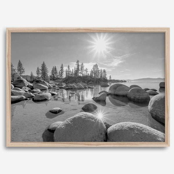 Capture the beauty of Lake Tahoe with this stunning black and white lake wall art. The image showcases majestic rocks rising from crystal-clear water. The reflection of the sun in the water adds a magical touch to the breathtaking scenery.