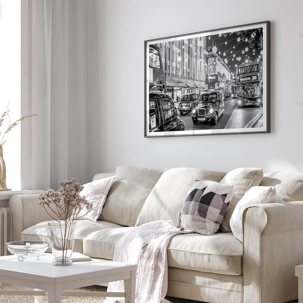 Black and white fine art photography print of a lively London street during Christmas, featuring double-decker buses, black taxis, and festive holiday lights.