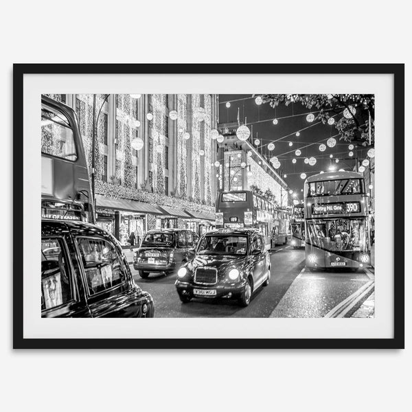Black and white fine art photography print of a lively London street during Christmas, featuring double-decker buses, black taxis, and festive holiday lights.