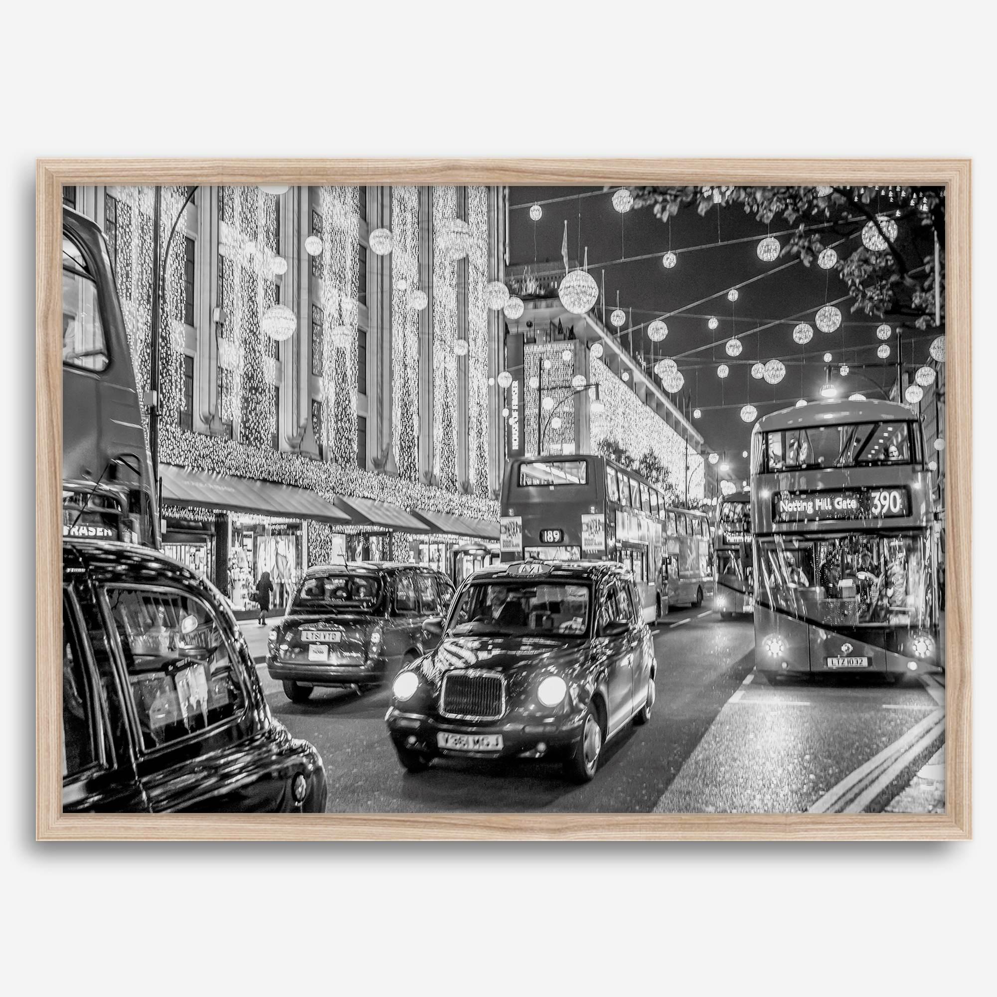 Black and white fine art photography print of a lively London street during Christmas, featuring double-decker buses, black taxis, and festive holiday lights.