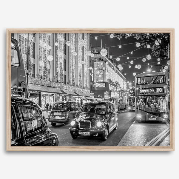 Black and white fine art photography print of a lively London street during Christmas, featuring double-decker buses, black taxis, and festive holiday lights.