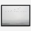 Minimalist seascape fine art print – a flock of birds in flight over a calm, misty ocean with a soft, gray horizon.