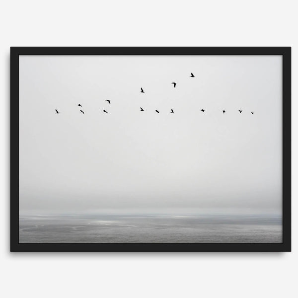 Minimalist seascape fine art print – a flock of birds in flight over a calm, misty ocean with a soft, gray horizon.