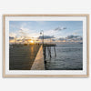 A fine art ocean sunset print featuring Pismo Beach Pier in Sunset with the surfers in the ocean and people enjoying a stroll on the pier.
