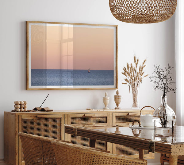 This stunning fine art ocean sunset photography print features a breathtaking scene of a boat against a golden and pink sky at sunset. The warm glow of the sunset and the natural beauty of the ocean and sky combine to create a soothing atmosphere.