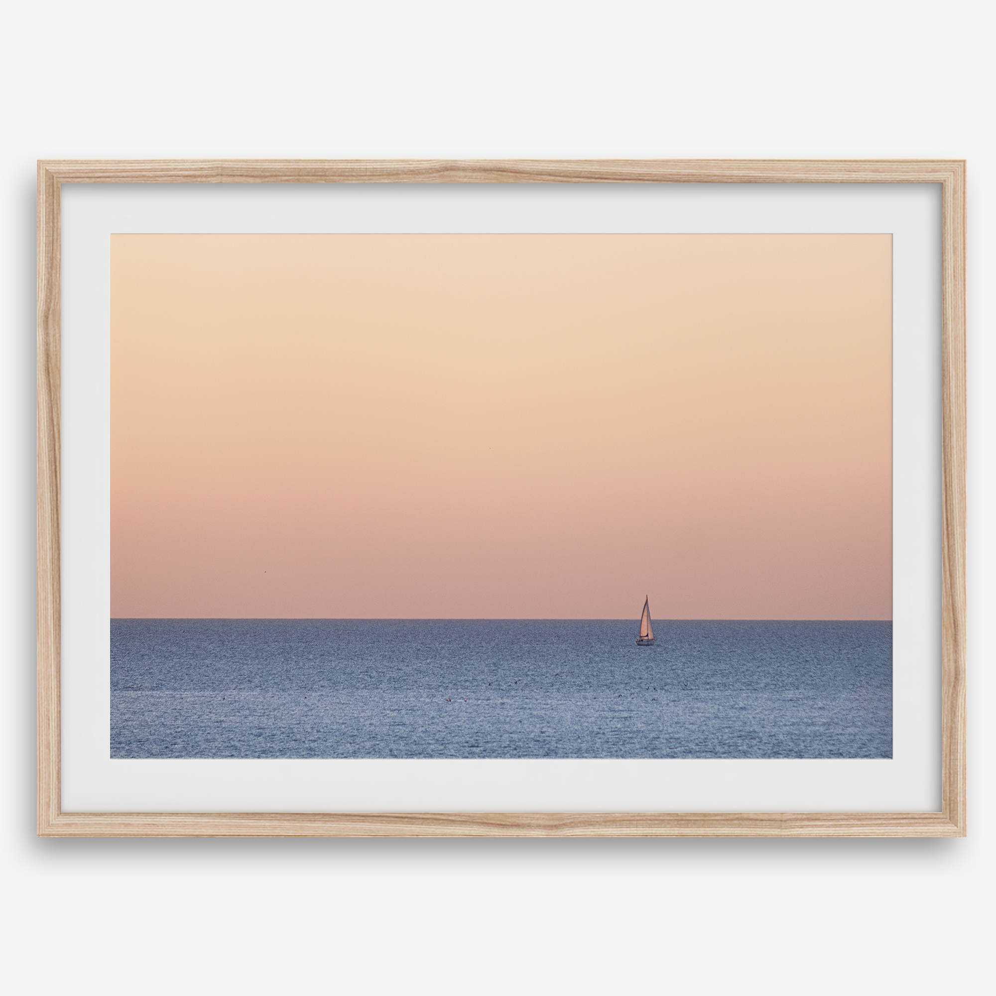 This stunning fine art ocean sunset photography print features a breathtaking scene of a boat against a golden and pink sky at sunset. The warm glow of the sunset and the natural beauty of the ocean and sky combine to create a soothing atmosphere.