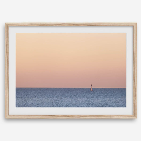 This stunning fine art ocean sunset photography print features a breathtaking scene of a boat against a golden and pink sky at sunset. The warm glow of the sunset and the natural beauty of the ocean and sky combine to create a soothing atmosphere.