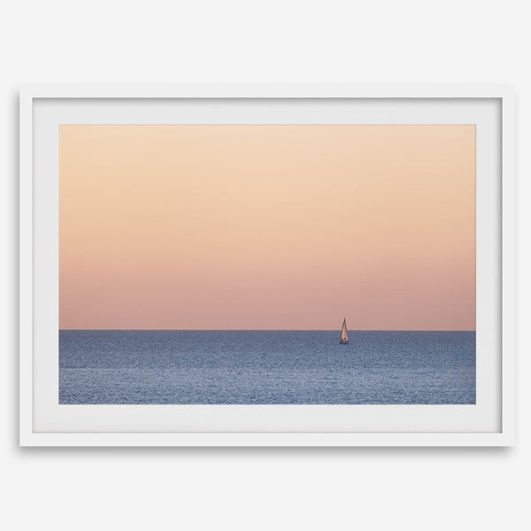 This stunning fine art ocean sunset photography print features a breathtaking scene of a boat against a golden and pink sky at sunset. The warm glow of the sunset and the natural beauty of the ocean and sky combine to create a soothing atmosphere.