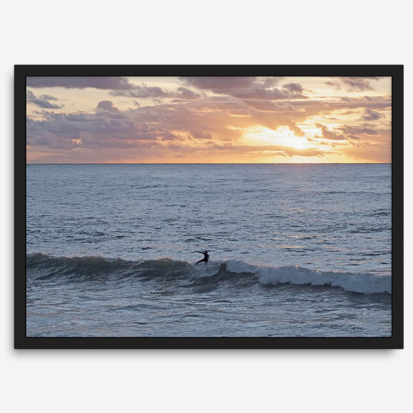 A fine art ocean sunset print showcasing a serene sunset and a lone surfer riding the waves. Taken in Montana De Oro State Park, California.