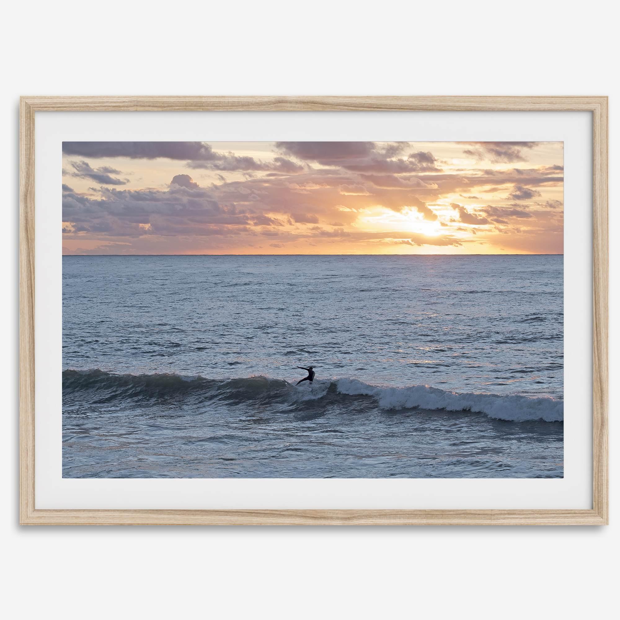 A fine art ocean sunset print showcasing a serene sunset and a lone surfer riding the waves. Taken in Montana De Oro State Park, California.