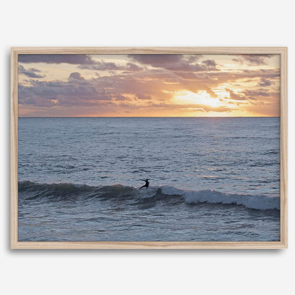 A fine art ocean sunset print showcasing a serene sunset and a lone surfer riding the waves. Taken in Montana De Oro State Park, California.