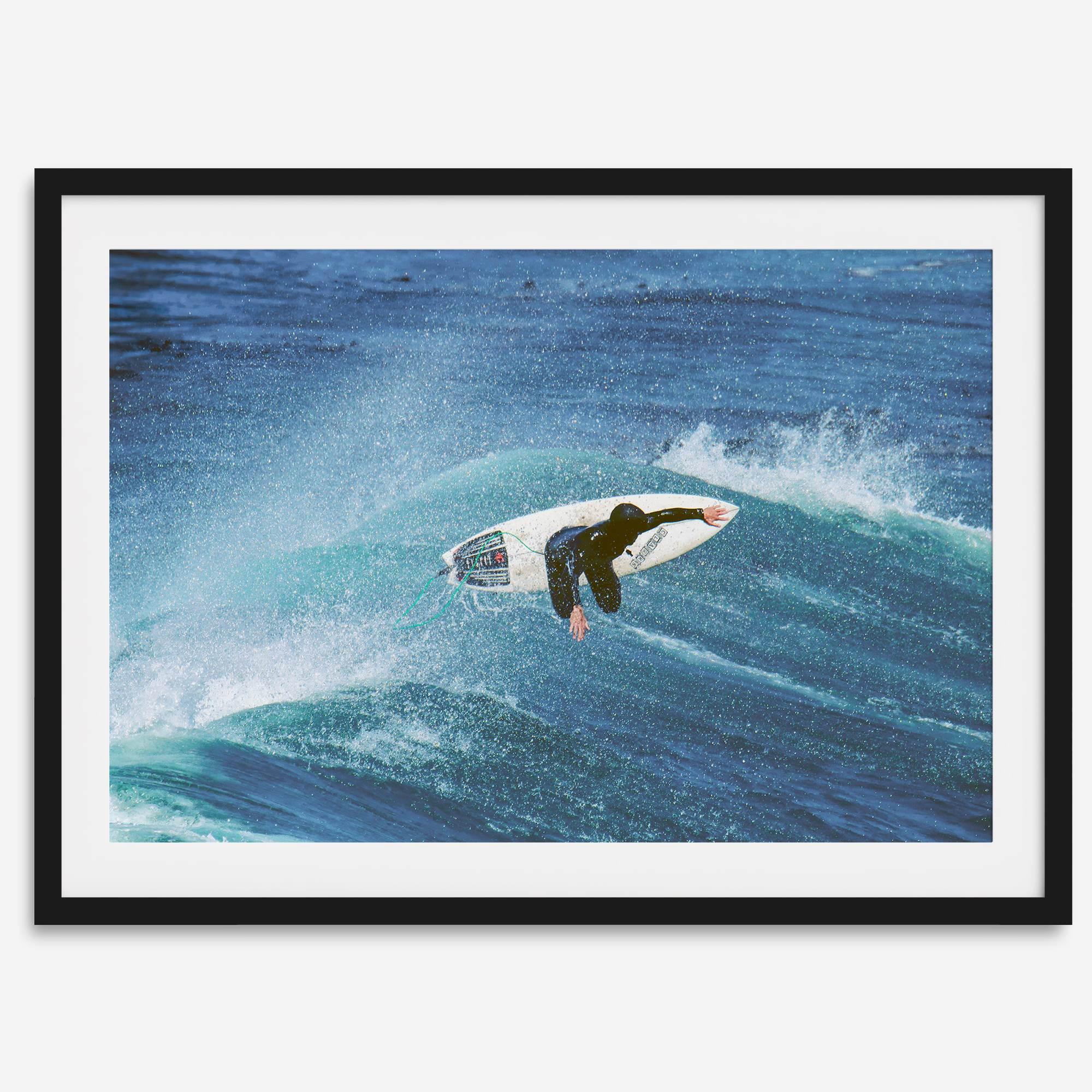 Surfer flying above a turquoise wave in Santa Cruz captured in vibrant ocean photography.