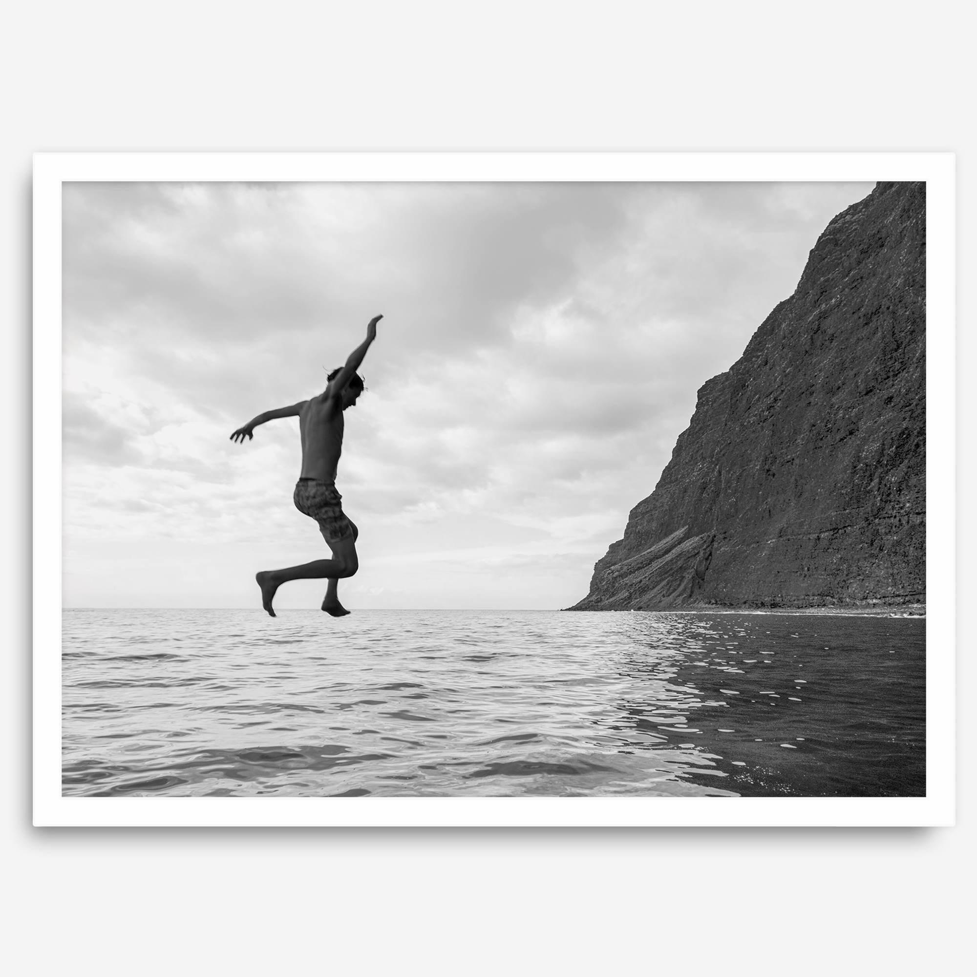 Black and white fine art print of a man mid-jump into the ocean near the cliffs of Na Pali Coast, Kauai.