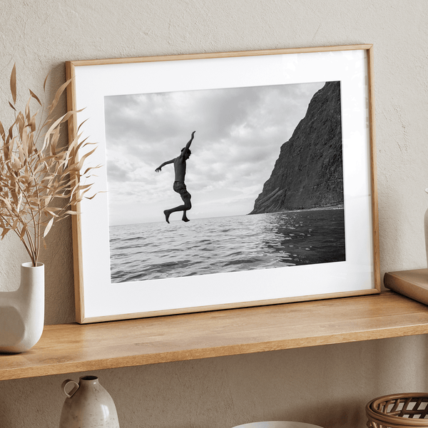 Black and white fine art print of a man mid-jump into the ocean near the cliffs of Na Pali Coast, Kauai.