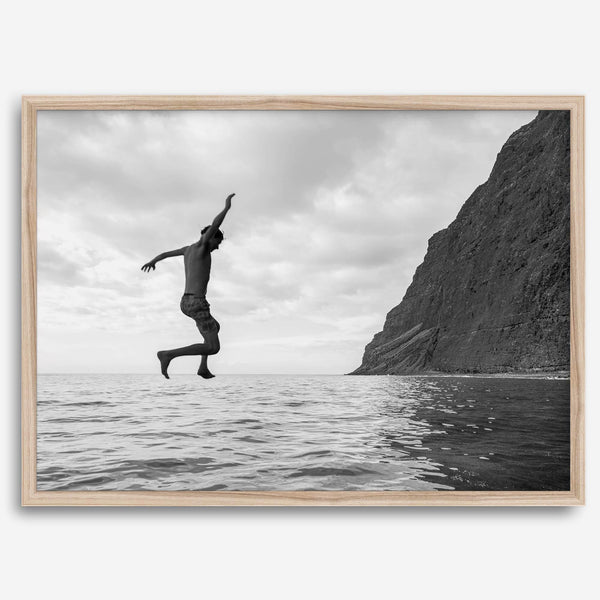 Black and white fine art print of a man mid-jump into the ocean near the cliffs of Na Pali Coast, Kauai.