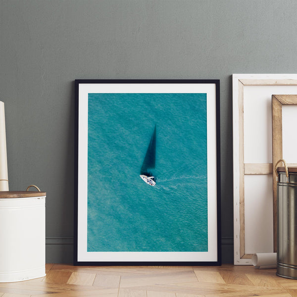 Aerial sailboat photography over turquoise San Francisco Bay near Berkeley, California, with a long sail-shaped shadow across the water.