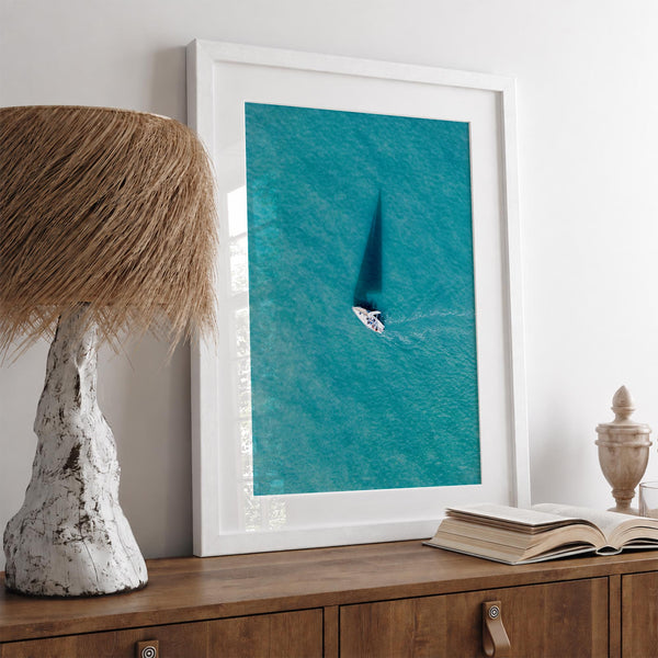 Aerial sailboat photography over turquoise San Francisco Bay near Berkeley, California, with a long sail-shaped shadow across the water.