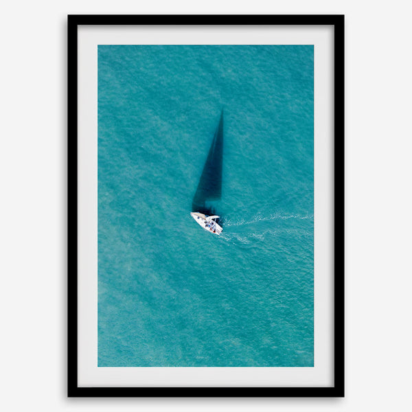 Aerial sailboat photography over turquoise San Francisco Bay near Berkeley, California, with a long sail-shaped shadow across the water.