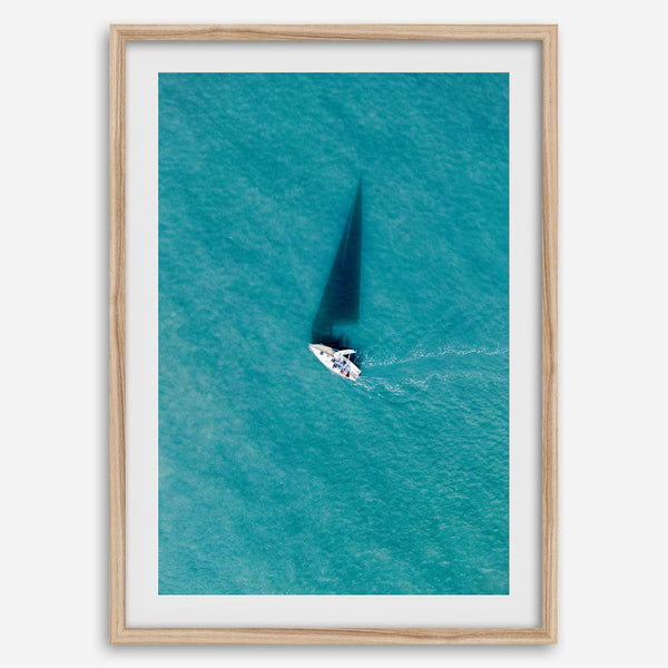 Aerial sailboat photography over turquoise San Francisco Bay near Berkeley, California, with a long sail-shaped shadow across the water.