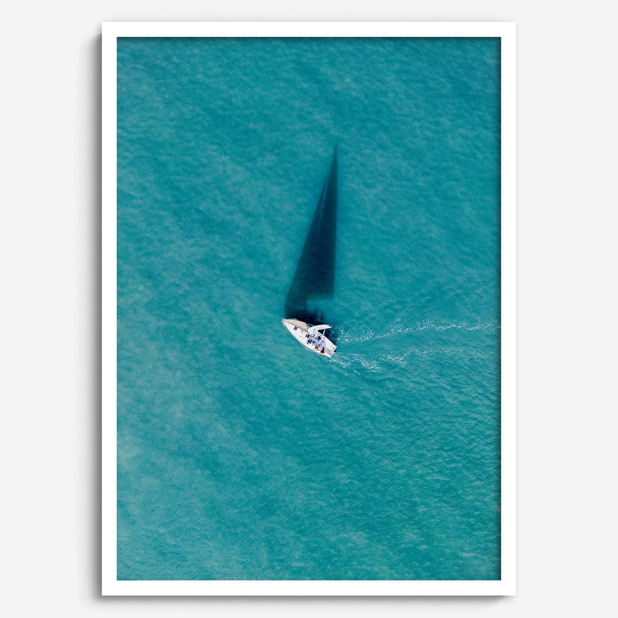 Aerial sailboat photography over turquoise San Francisco Bay near Berkeley, California, with a long sail-shaped shadow across the water.