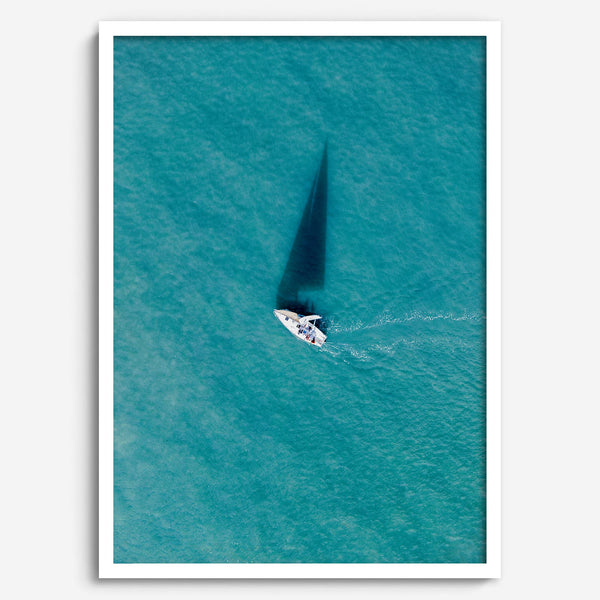 Aerial sailboat photography over turquoise San Francisco Bay near Berkeley, California, with a long sail-shaped shadow across the water.