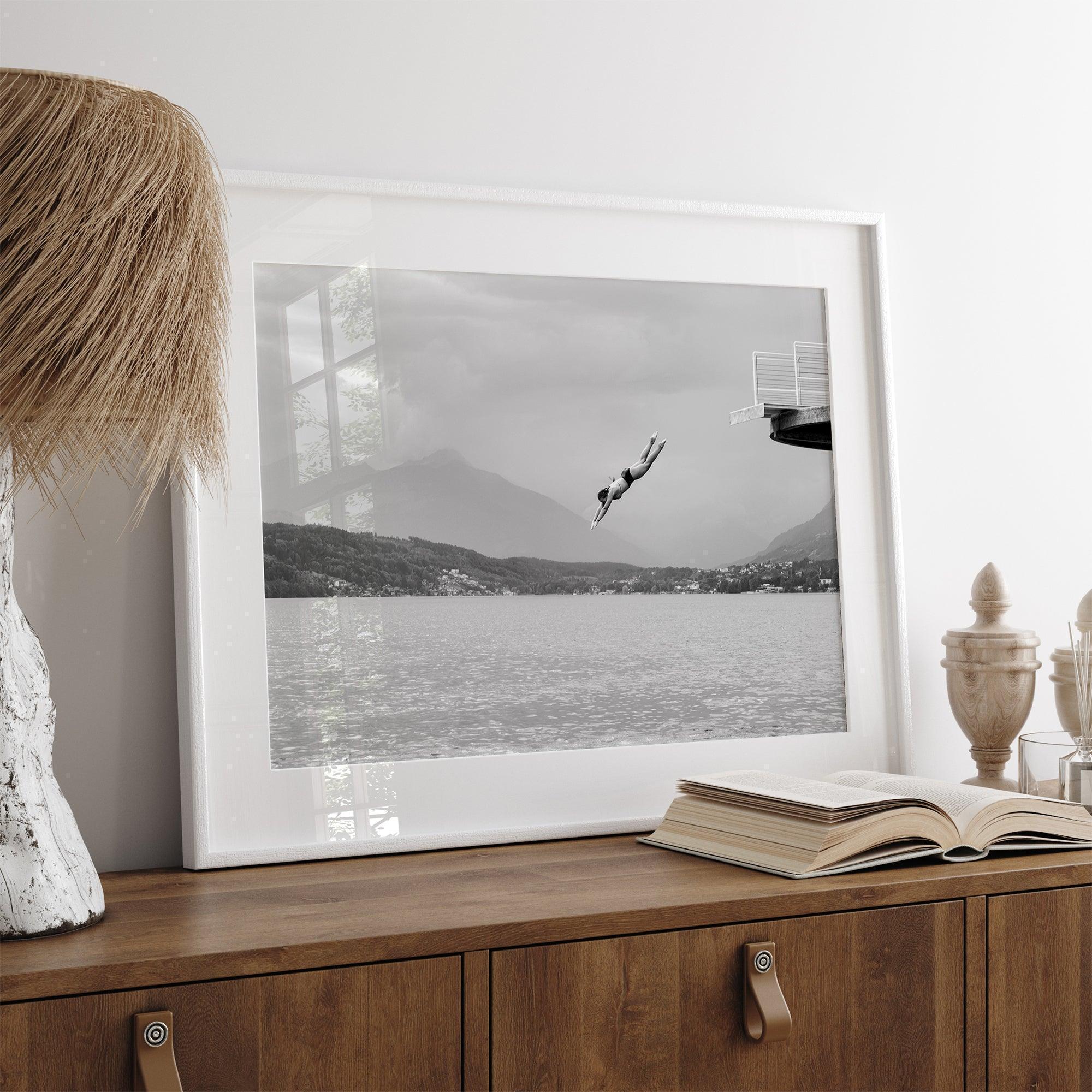 Diver leaping from a platform over a serene Austrian lake, with misty mountains in the background.