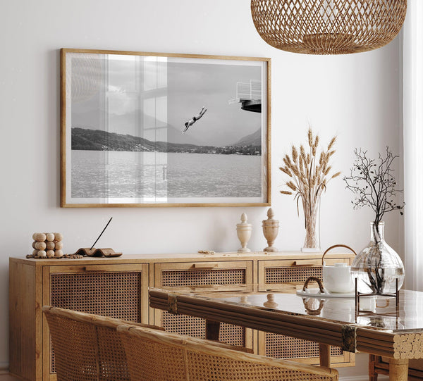 Diver leaping from a platform over a serene Austrian lake, with misty mountains in the background.