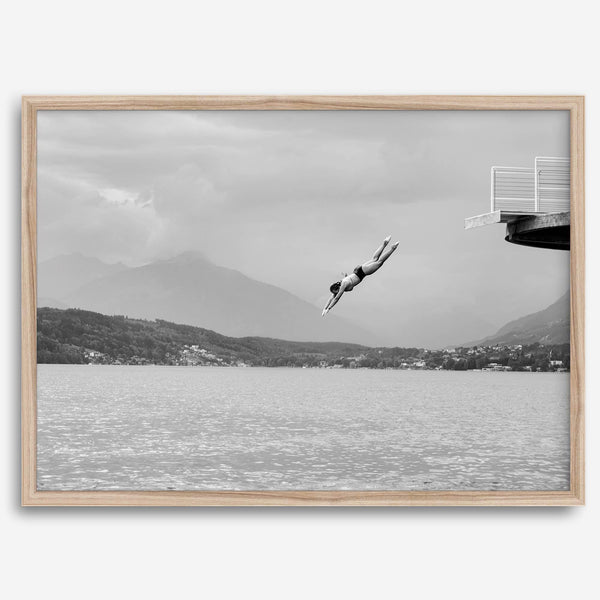 Diver leaping from a platform over a serene Austrian lake, with misty mountains in the background.