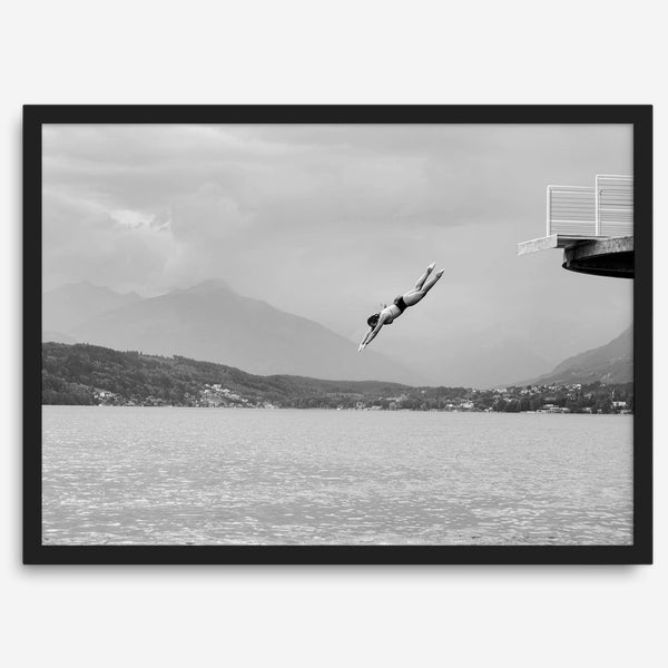 Diver leaping from a platform over a serene Austrian lake, with misty mountains in the background.