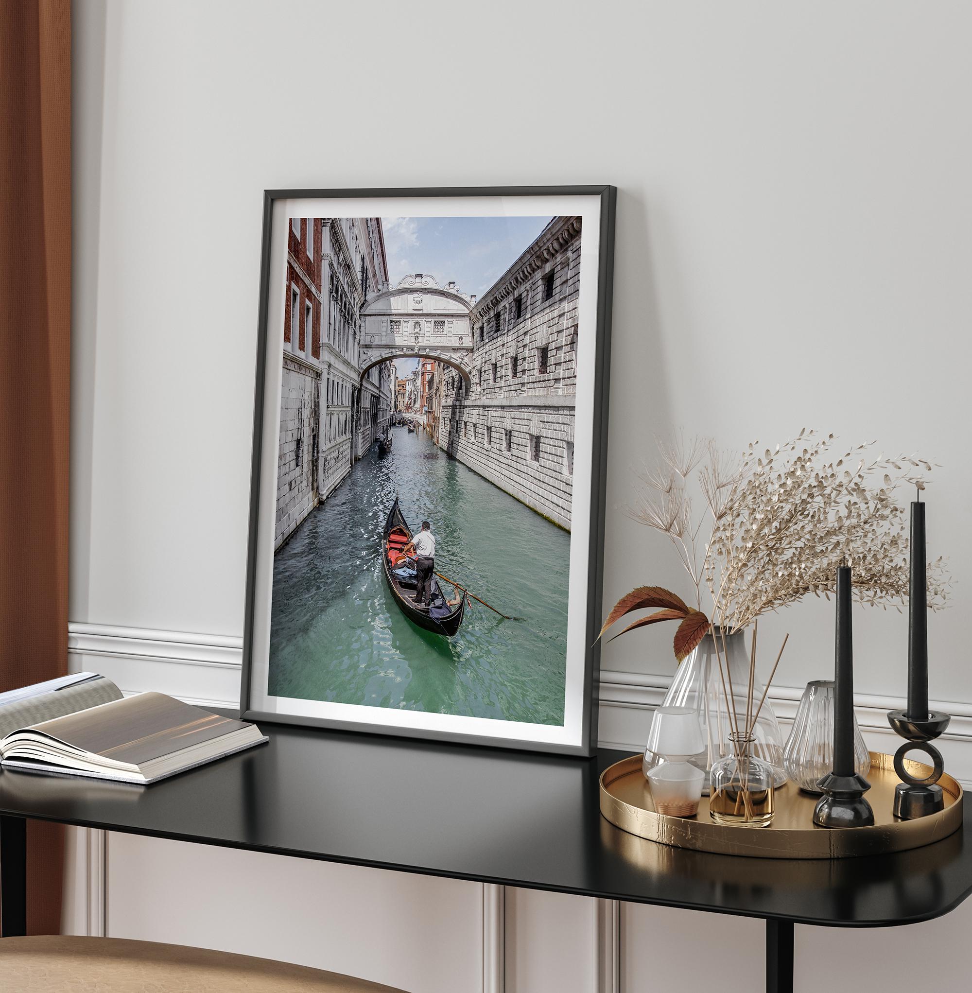 Venice canal photography print featuring a gondola approaching the Bridge of Sighs between historic stone buildings in Venice, Italy.