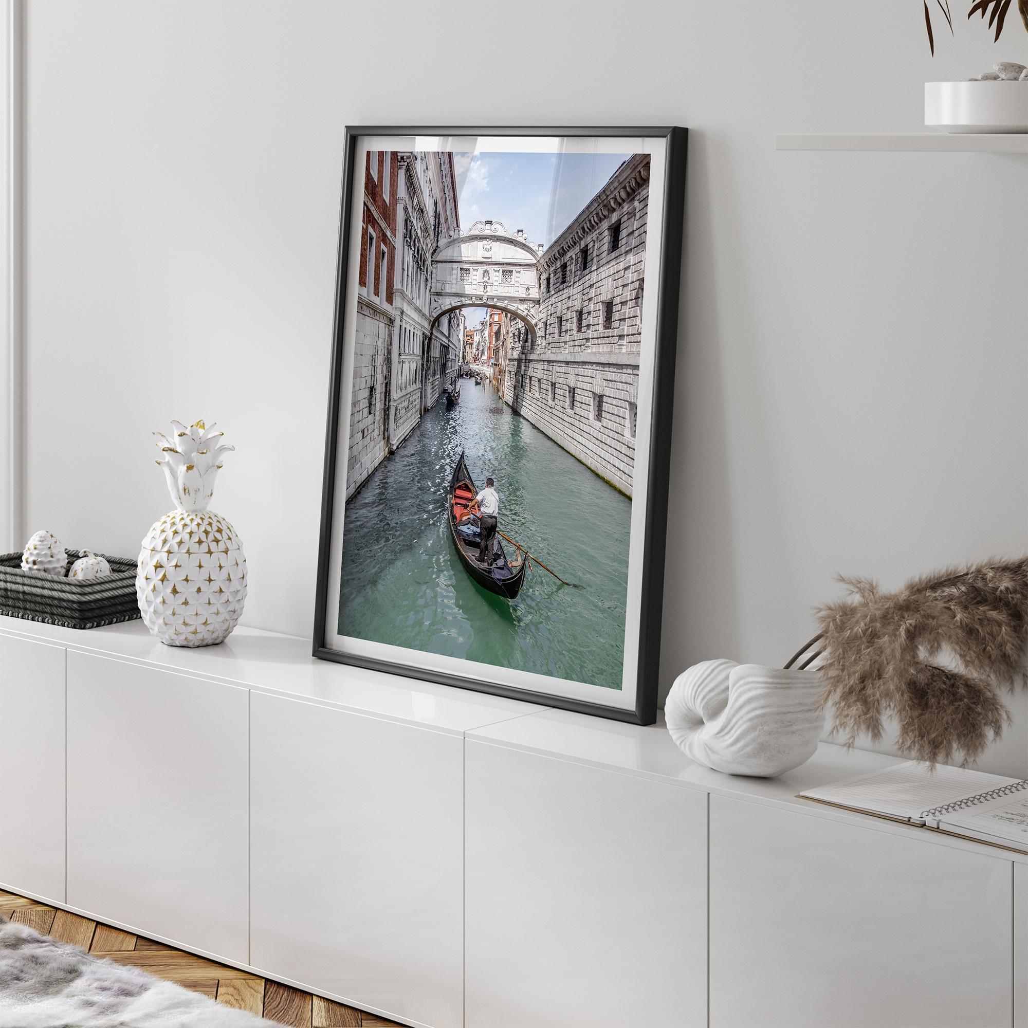 Venice canal photography print featuring a gondola approaching the Bridge of Sighs between historic stone buildings in Venice, Italy.