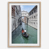 Venice canal photography print featuring a gondola approaching the Bridge of Sighs between historic stone buildings in Venice, Italy.