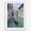 Venice canal photography print featuring a gondola approaching the Bridge of Sighs between historic stone buildings in Venice, Italy.
