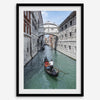 Venice canal photography print featuring a gondola approaching the Bridge of Sighs between historic stone buildings in Venice, Italy.