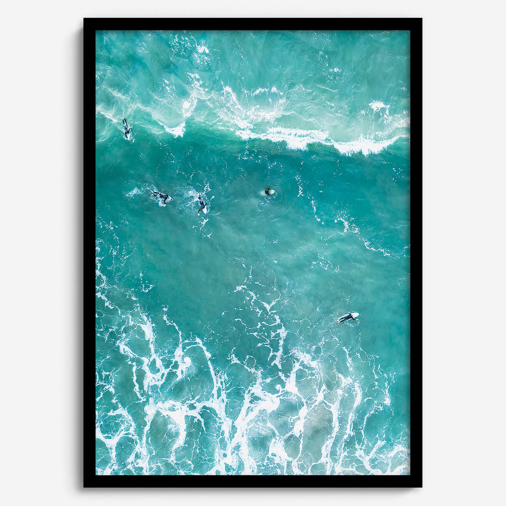 A fine art aerial ocean photography print showing surfers paddling for waves. Stunning blue wall art for home decor. 