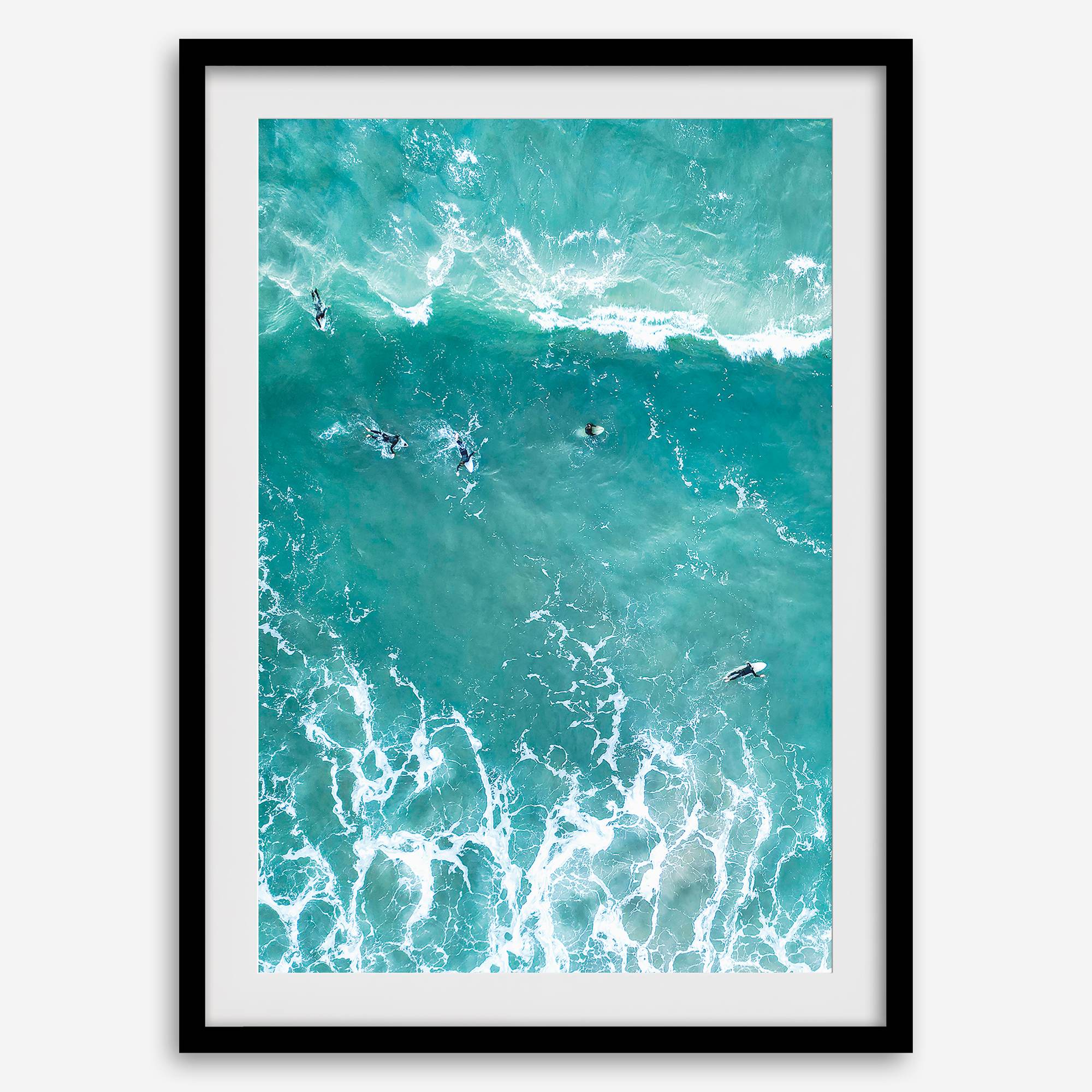 A fine art aerial ocean photography print showing surfers paddling for waves. Stunning blue wall art for home decor. 