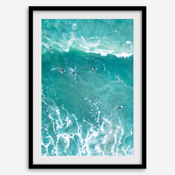 A fine art aerial ocean photography print showing surfers paddling for waves. Stunning blue wall art for home decor. 