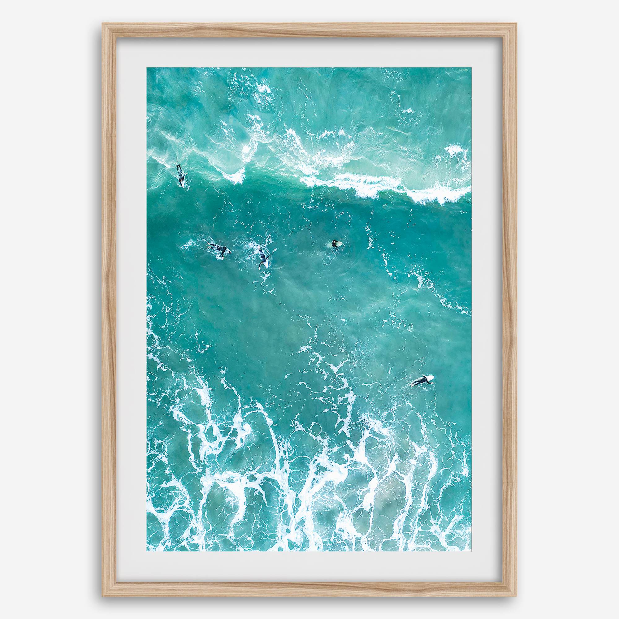 A fine art aerial ocean photography print showing surfers paddling for waves. Stunning blue wall art for home decor. 