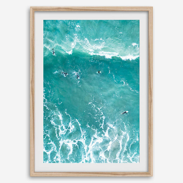 A fine art aerial ocean photography print showing surfers paddling for waves. Stunning blue wall art for home decor. 