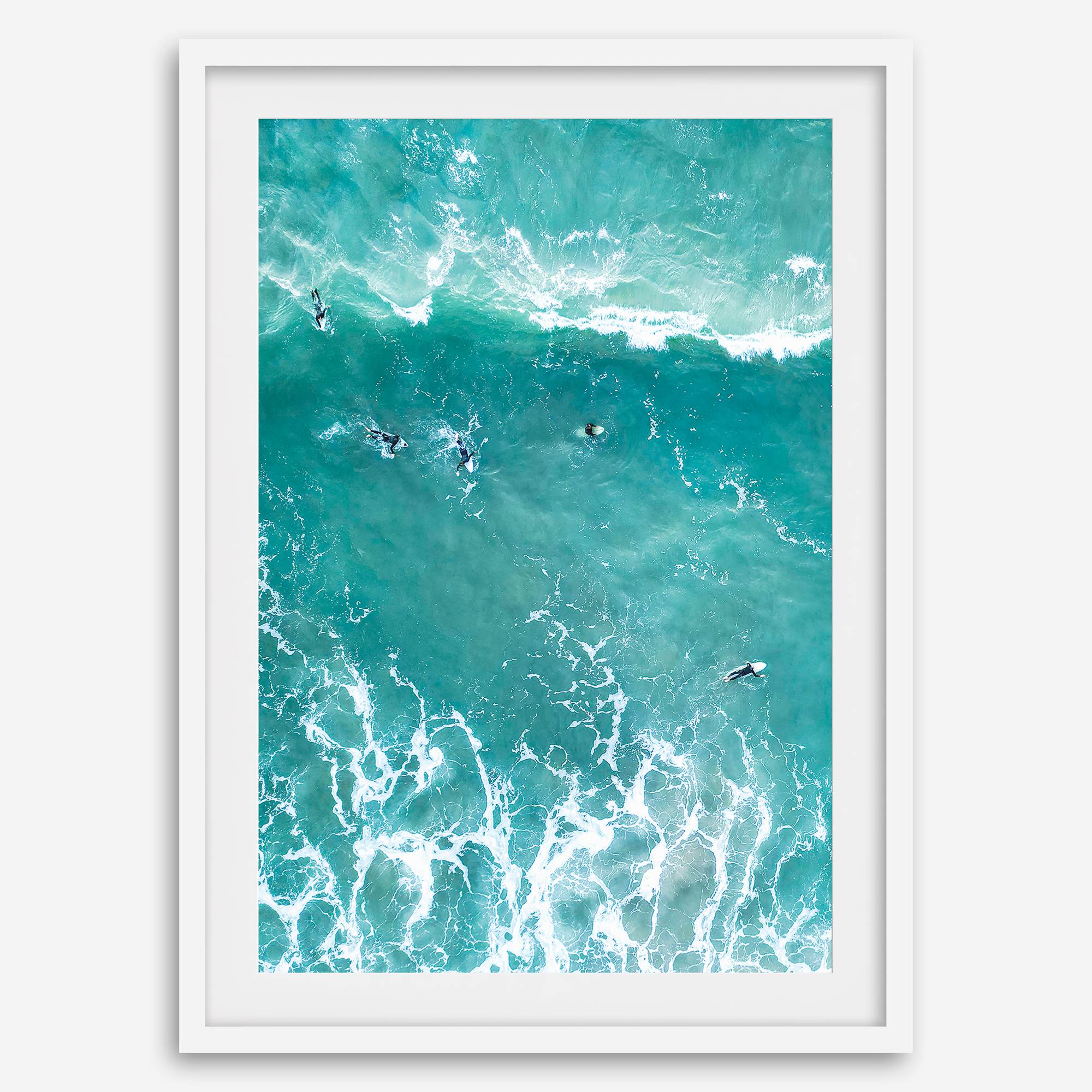 A fine art aerial ocean photography print showing surfers paddling for waves. Stunning blue wall art for home decor. 