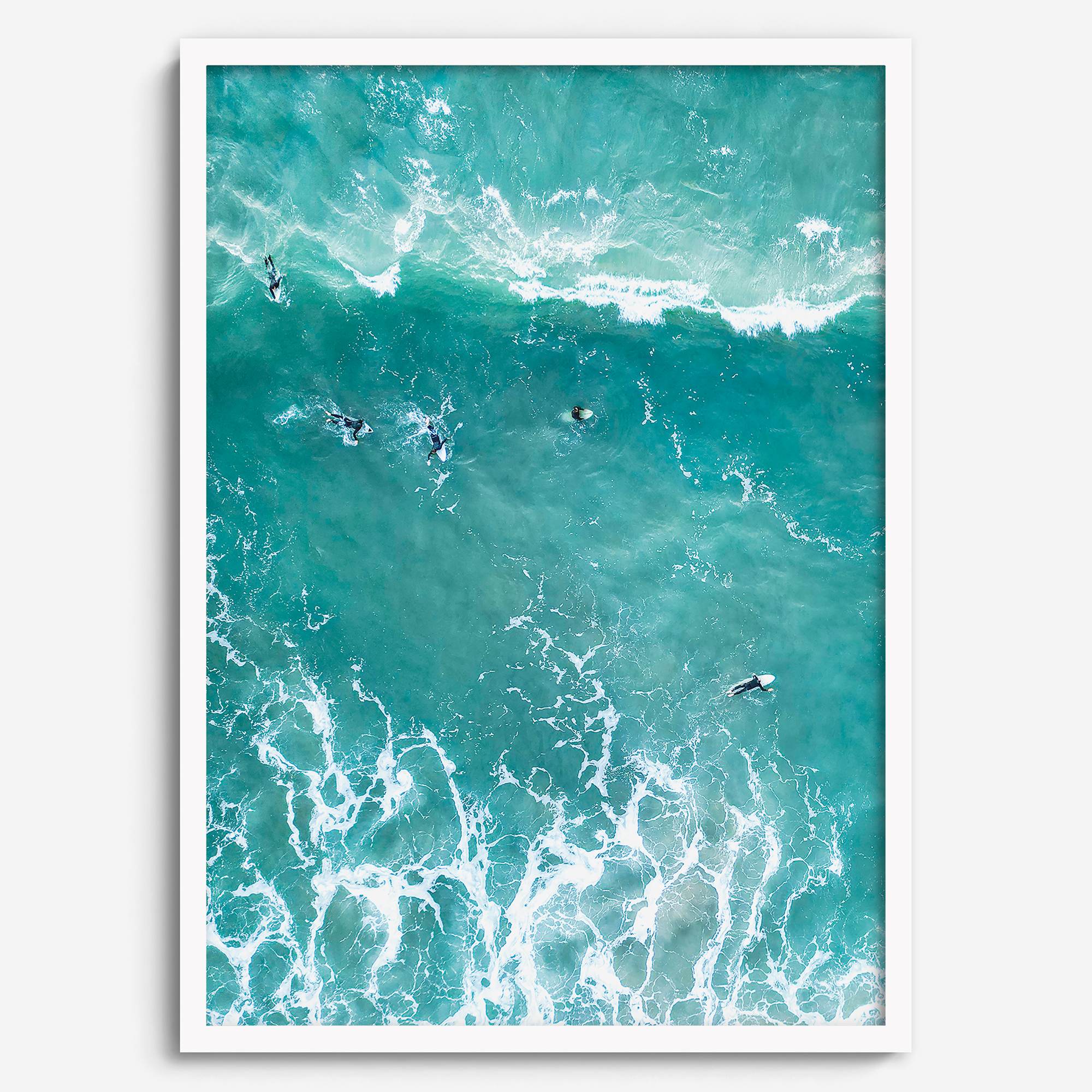 A fine art aerial ocean photography print showing surfers paddling for waves. Stunning blue wall art for home decor. 