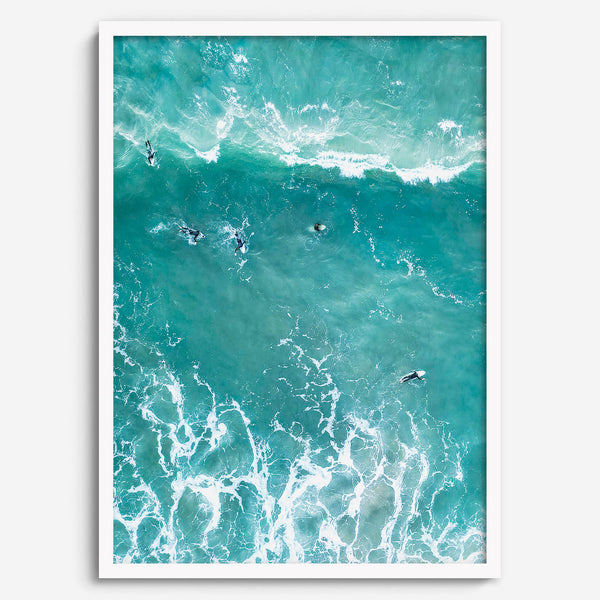 A fine art aerial ocean photography print showing surfers paddling for waves. Stunning blue wall art for home decor. 