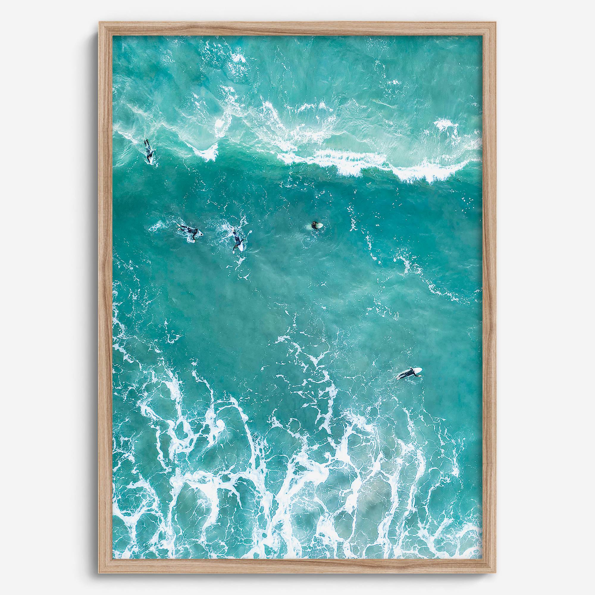 A fine art aerial ocean photography print showing surfers paddling for waves. Stunning blue wall art for home decor. 