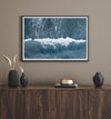 Aerial ocean wall art featuring a lone surfer and a breaking white wave in the deep blue waters of Hanalei Bay.